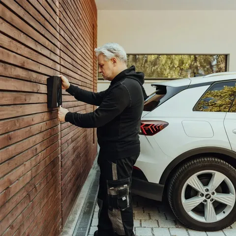 Handwerker arbeitet an einer holzverkleideten Hauswand